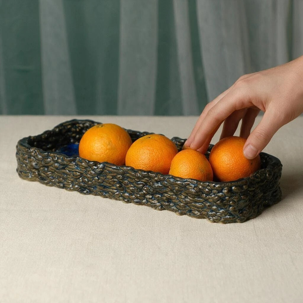 Glossy deep blue 3D printed ceramic fruit tray with woven texture filled with fresh oranges on a beige table setting #color_sapphire blue