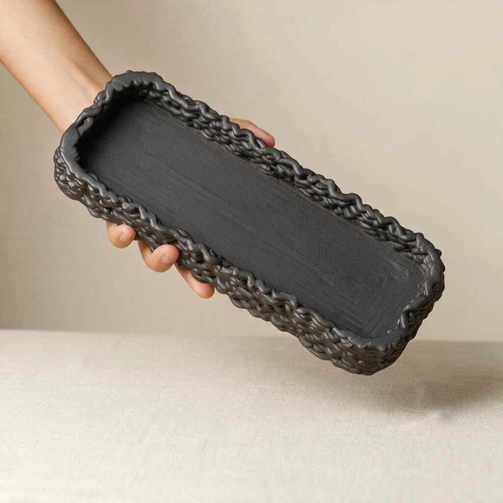 Hand holding a matte black 3D printed ceramic rectangular tray showcasing product size and woven detail #color_black