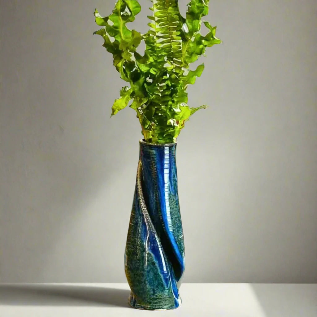 Shining blue vase decorated with green leaves placed on a coffee table in a living room #color_sapphire blue