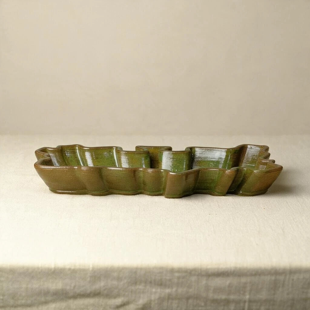 Side shot of a ceramic long tray in olive green glossy finish. The 3d printed ceramic tray is set against a beige background. #color_olive green