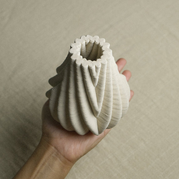 Ceramic bud vase with intricate grooves held in a hand #color_white