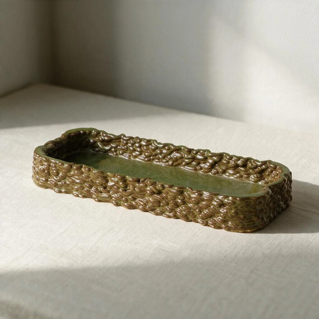 Empty glossy olive green 3D printed ceramic decorative tray with intricate woven texture sitting on a beige linen tablecloth in natural sunlight #color_olive green