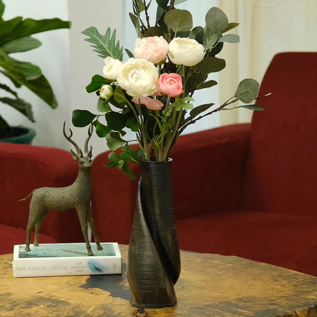 Glazed matte black vase decorated with flowers placed in a living room on a coffee table #color_black