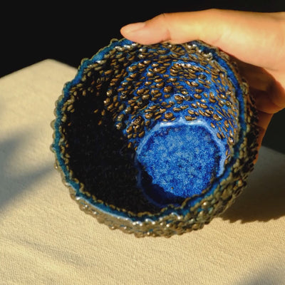 Mulberry sculptural ceramic bowl in blue glossy glaze shown in sunlight. The video shows how the 3d printed ceramic texture of the bowl catches light and shines